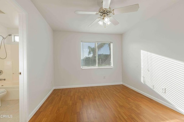 spare room featuring visible vents, baseboards, light wood-style floors, and a ceiling fan