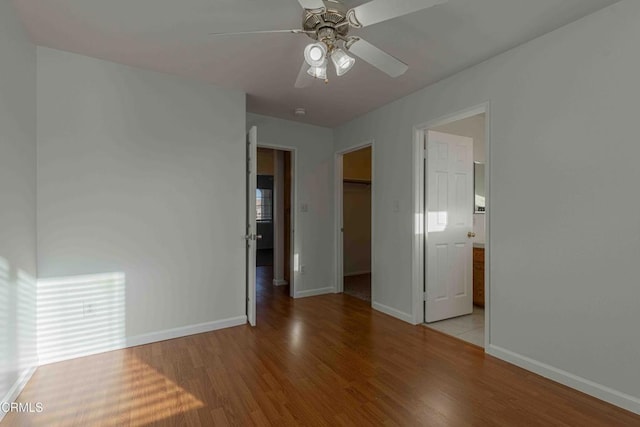 empty room featuring ceiling fan, baseboards, and wood finished floors