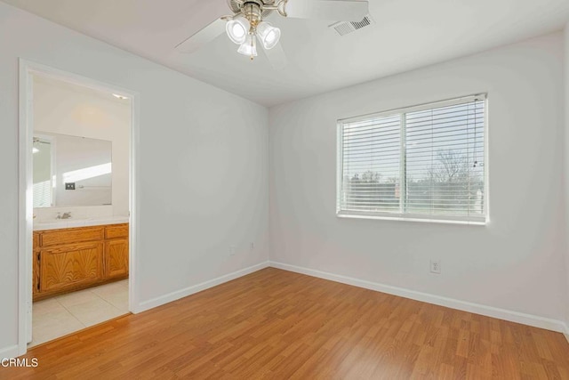 unfurnished bedroom with visible vents, light wood-type flooring, baseboards, and a sink