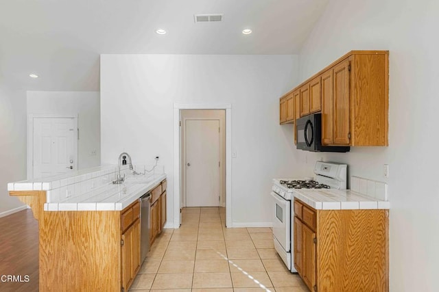 kitchen featuring visible vents, gas range gas stove, a peninsula, black microwave, and dishwasher