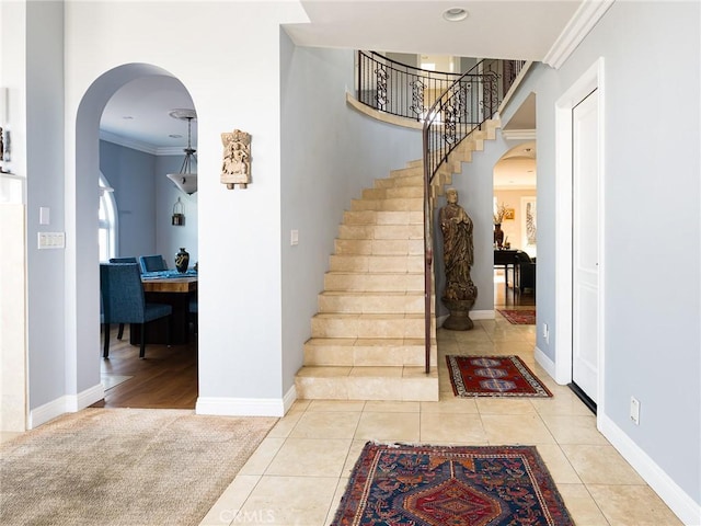 foyer with light tile patterned floors, arched walkways, and ornamental molding