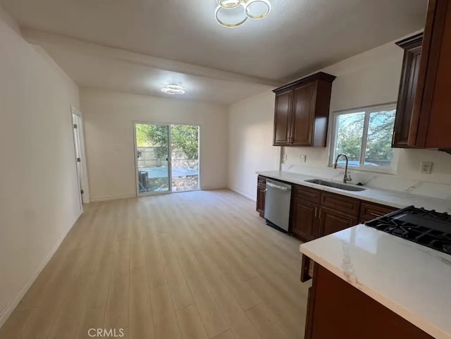 kitchen with baseboards, light wood-style flooring, a sink, light countertops, and stainless steel dishwasher