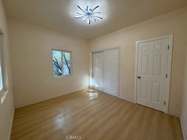 unfurnished bedroom with a closet, baseboards, and light wood finished floors