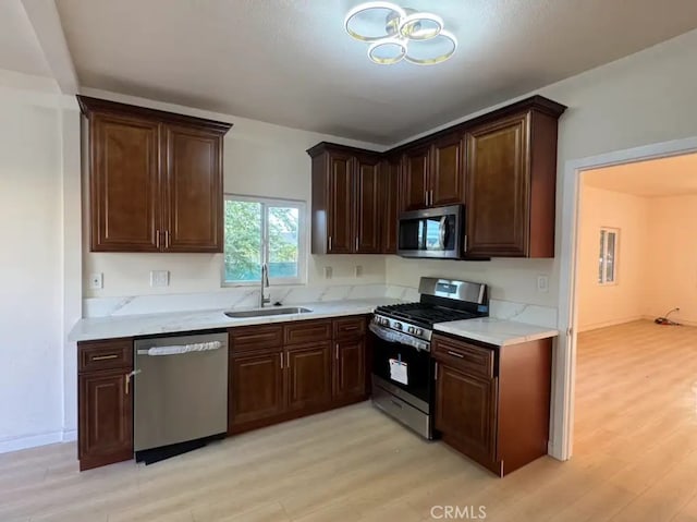 kitchen with a sink, light countertops, light wood-style floors, and stainless steel appliances