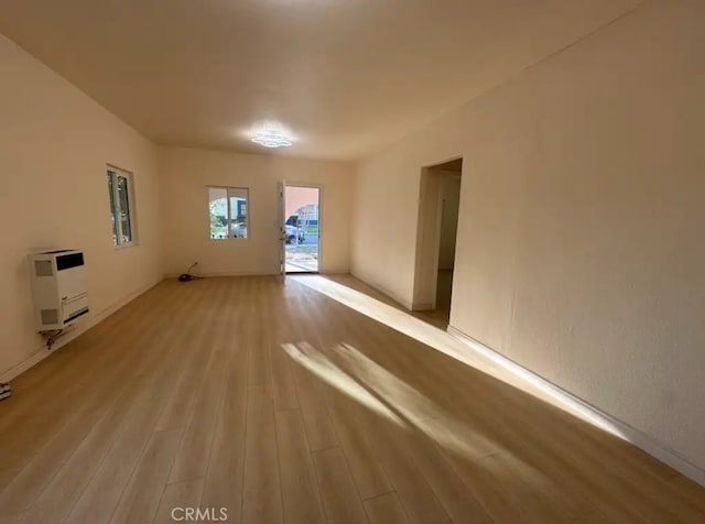 empty room with heating unit and light wood-style floors