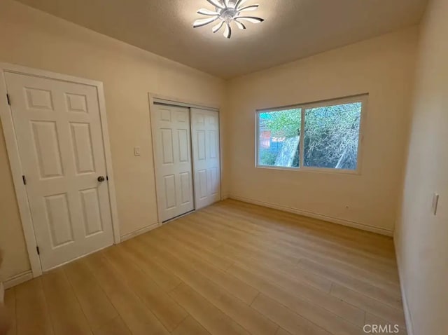 unfurnished bedroom with baseboards, a closet, and light wood finished floors