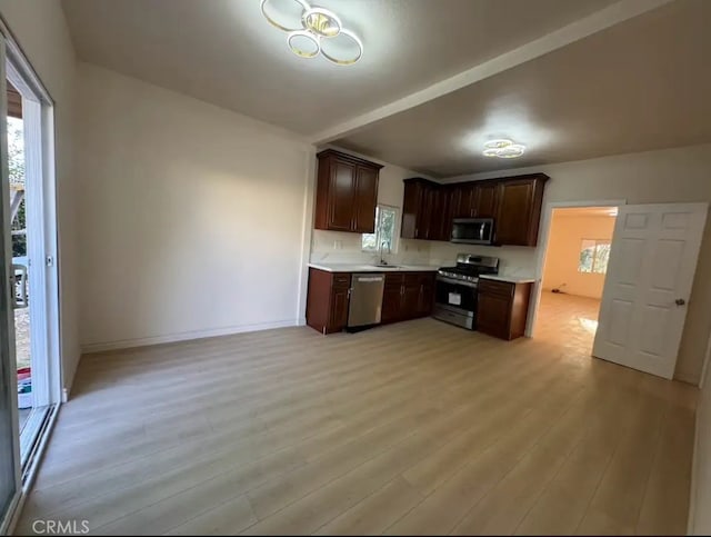 kitchen with light wood-type flooring, stainless steel appliances, baseboards, and light countertops