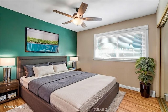 bedroom with a ceiling fan, wood finished floors, baseboards, and a closet