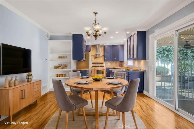 dining room featuring a notable chandelier, baseboards, light wood-style floors, and ornamental molding