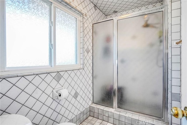 bathroom with an enclosed shower, toilet, and tile walls