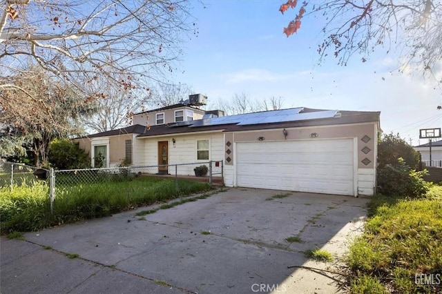 view of front of property featuring a garage, roof mounted solar panels, concrete driveway, and fence