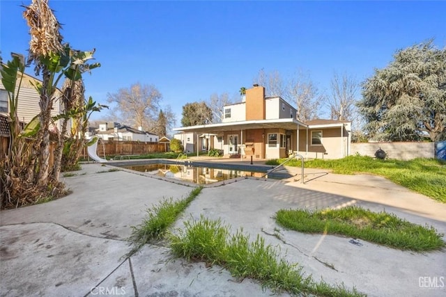 rear view of property with a patio area, a chimney, and fence