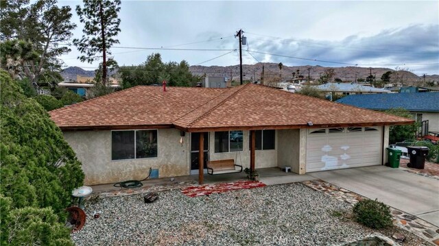 ranch-style house featuring stucco siding, driveway, roof with shingles, and an attached garage