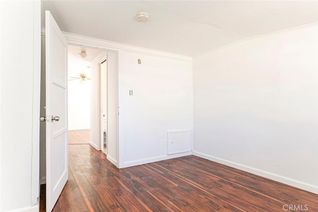 unfurnished room featuring dark wood-type flooring, baseboards, and ornamental molding