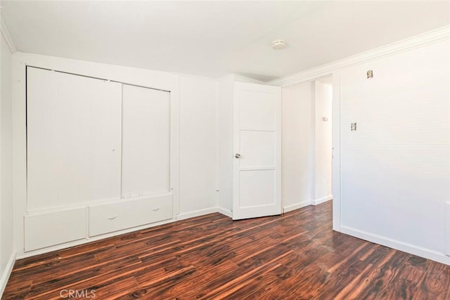 unfurnished bedroom with dark wood-type flooring, baseboards, a closet, and ornamental molding