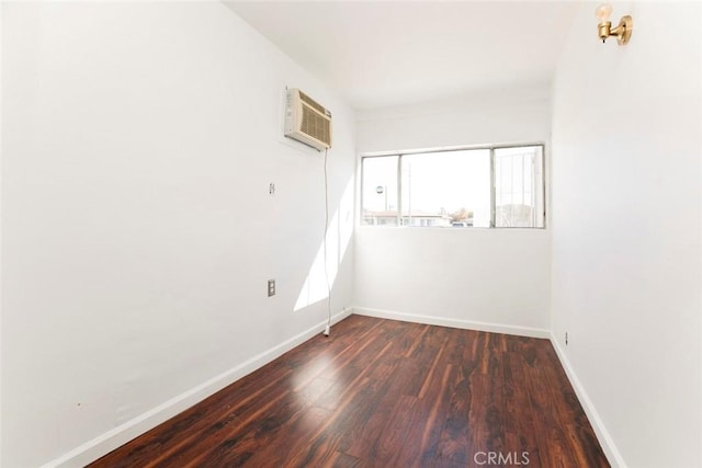 unfurnished room with a wall mounted AC, baseboards, and wood finished floors