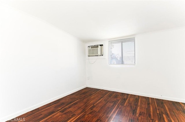 empty room featuring crown molding, baseboards, dark wood-style flooring, and a wall mounted AC