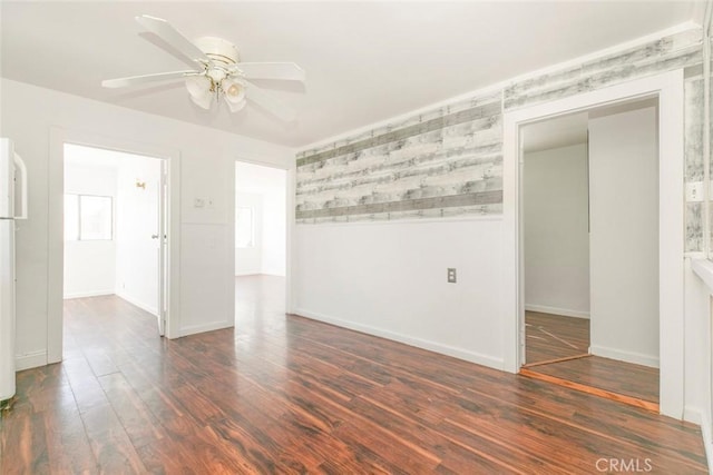 spare room featuring wood finished floors, baseboards, and ceiling fan