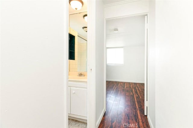 corridor featuring a sink, baseboards, and wood-type flooring