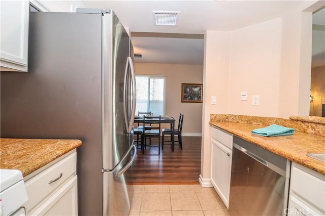 kitchen featuring visible vents, light tile patterned floors, light stone counters, stainless steel appliances, and white cabinetry