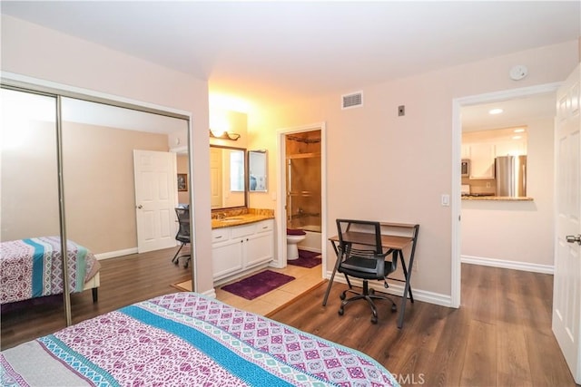 bedroom featuring a closet, visible vents, wood finished floors, and freestanding refrigerator