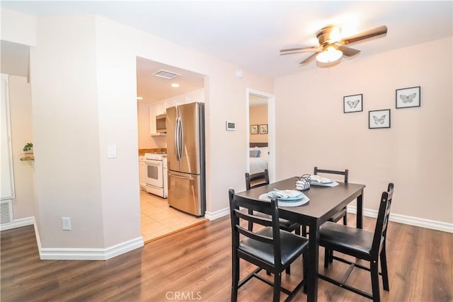 dining space with wood finished floors, a ceiling fan, and baseboards