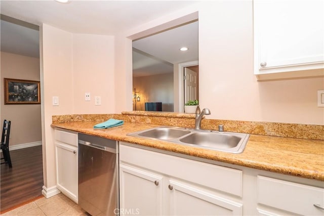 kitchen with light tile patterned floors, white cabinetry, a sink, light countertops, and stainless steel dishwasher