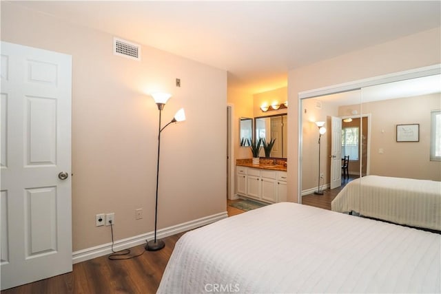 bedroom featuring visible vents, baseboards, connected bathroom, and dark wood-style flooring