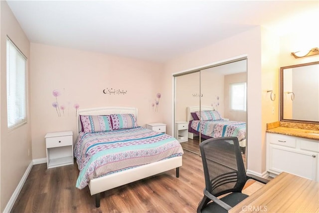 bedroom with wood finished floors, baseboards, and a closet