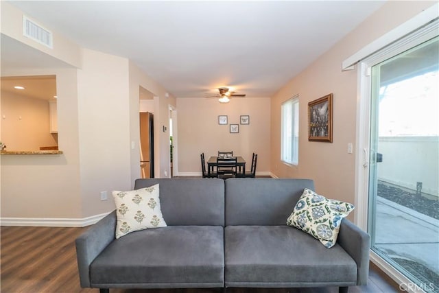 living room with visible vents, baseboards, dark wood finished floors, and a ceiling fan