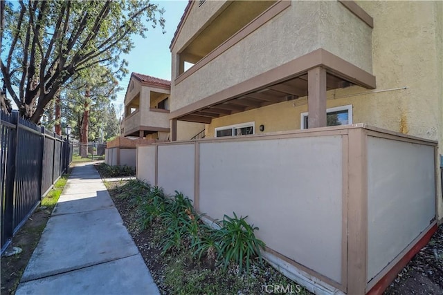 view of side of home featuring stucco siding and fence