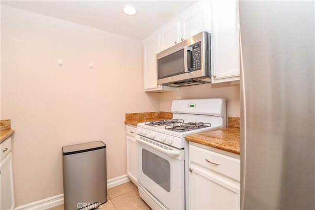 kitchen featuring light tile patterned floors, baseboards, light countertops, appliances with stainless steel finishes, and white cabinetry