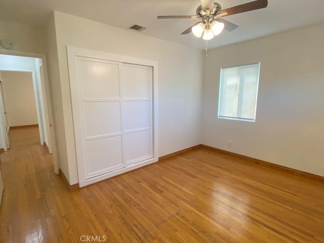 unfurnished bedroom with visible vents, light wood-style flooring, a ceiling fan, a closet, and baseboards