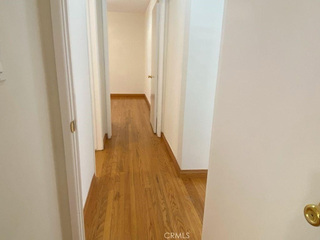 hall featuring baseboards and light wood-style flooring