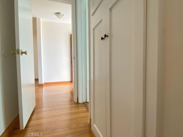 hallway featuring baseboards and light wood-type flooring