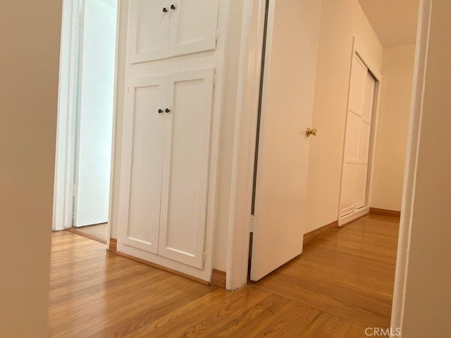 corridor featuring baseboards and light wood-type flooring