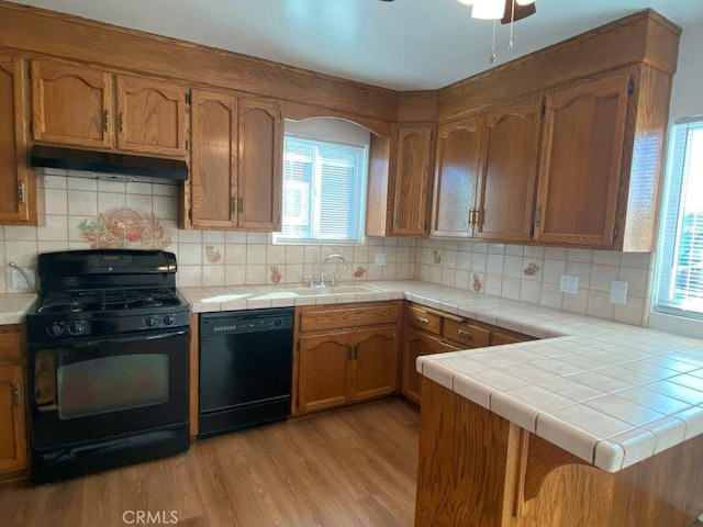 kitchen with black appliances, plenty of natural light, light wood-style floors, and under cabinet range hood