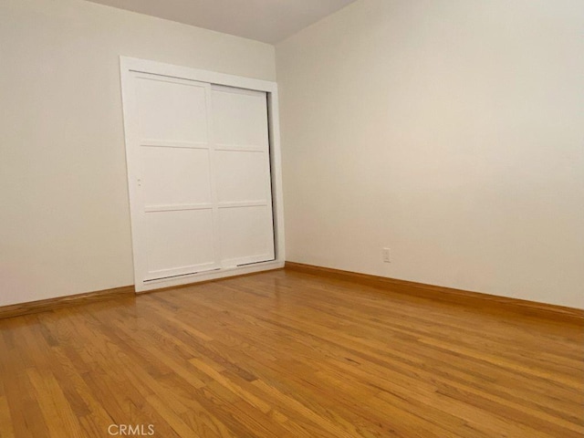 unfurnished bedroom featuring a closet, baseboards, and light wood-style floors