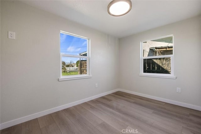 spare room with baseboards and wood finished floors