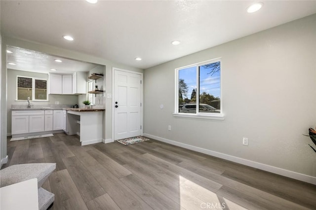 kitchen featuring a sink, open shelves, white cabinets, baseboards, and dark wood-style flooring