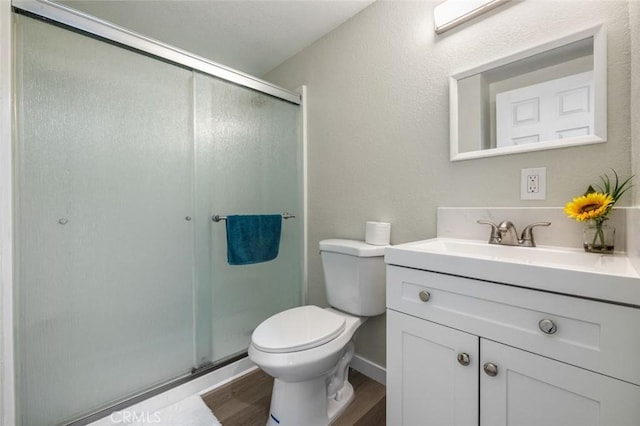 full bathroom featuring a stall shower, toilet, wood finished floors, and vanity