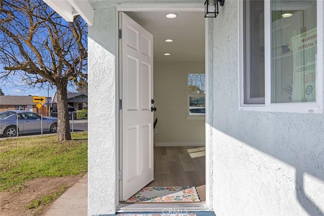 property entrance featuring stucco siding, a yard, and fence