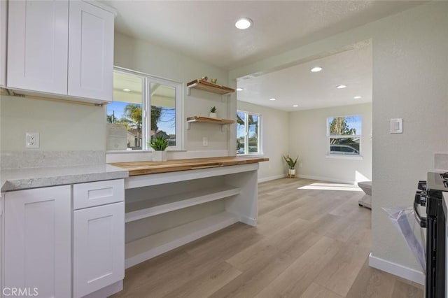 kitchen with range with gas stovetop, open shelves, light wood-style flooring, and white cabinets