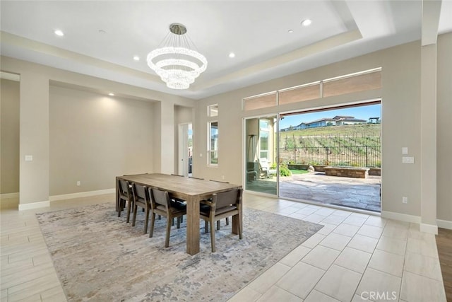 dining area featuring recessed lighting, baseboards, a raised ceiling, and a notable chandelier