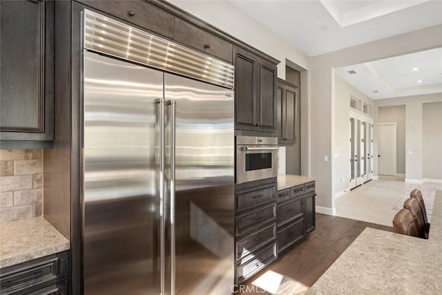 kitchen with stainless steel appliances, dark brown cabinets, dark wood-style flooring, and light countertops