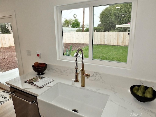 details featuring a sink, light stone countertops, and dishwasher