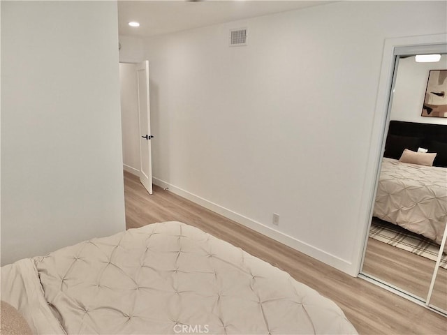 bedroom with wood finished floors, visible vents, and baseboards