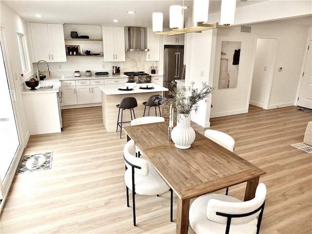 dining area with visible vents, light wood-type flooring, and baseboards