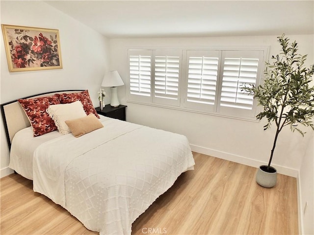 bedroom with baseboards and wood finished floors