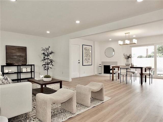 living room featuring light wood finished floors, recessed lighting, baseboards, and an inviting chandelier